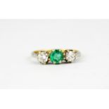 An 18ct white gold ring set with a round cut emerald flanked by brilliant cut diamonds, approx. 0.