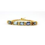 A yellow metal (tested 18ct gold) bracelet set with baguette cut blue topaz and brilliant cut