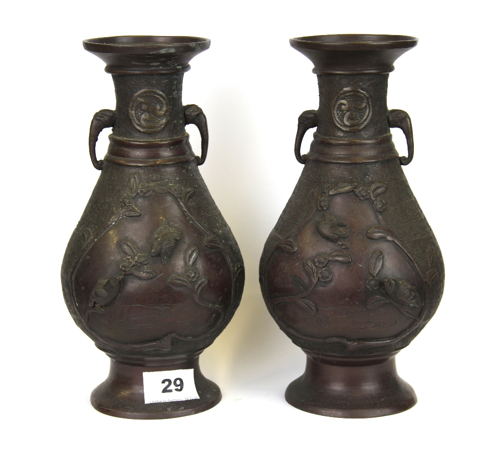 A pair of Japanese bronze vases decorated with panels of birds and with elephant head handles, H.