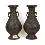 A pair of Japanese bronze vases decorated with panels of birds and with elephant head handles, H.
