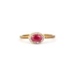 A 9ct yellow gold oval cut ruby and diamond set halo ring, (O).