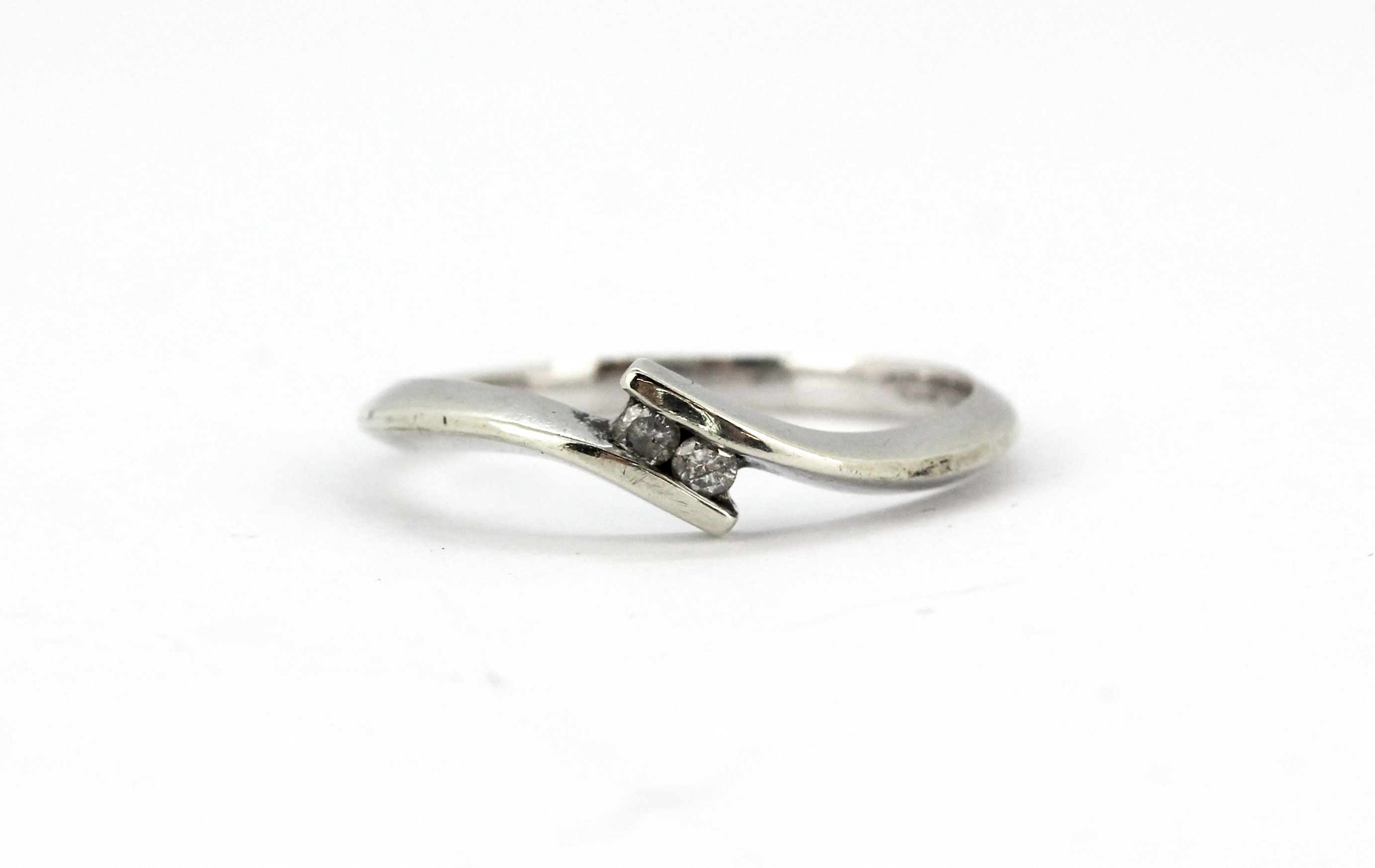 A 9ct white gold diamond set crossover ring, (N).