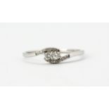 A 9ct white gold diamond set crossover ring, (S).