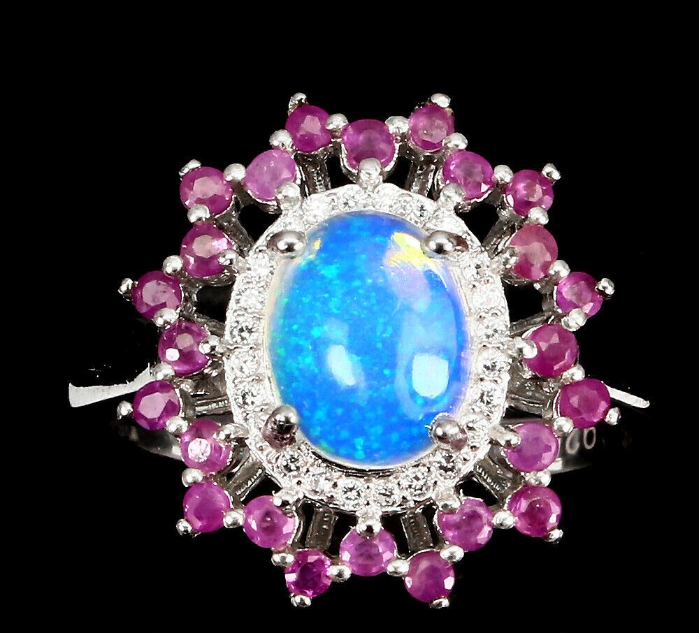 A 925 silver cluster ring set with a cabochon cut opal surrounded by rubies, (R.5).