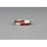 A yellow metal (tested minimum 9ct gold) ring set with step cut rubies and brilliant cut