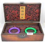 A Chinese wooden presentation box containing two jade bangles, internal Dia. 6cm. W. 13.5mm.