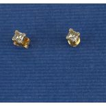 A pair of yellow metal (tested 18ct yellow gold) stud earrings set with princess cut diamonds,