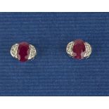 A pair of 14ct white gold (stamped 585) stud earrings set with oval cut rubies and brilliant cut