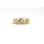 An 18ct yellow gold gipsy ring set with three old cut diamonds, (N).