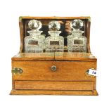 An oak mirror backed and brass mounted Victorian tantalus with four cut glass decanters and silver
