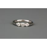 A white metal (tested 18ct white gold) ring set with three brilliant cut diamonds, (K).