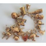 A 9ct gold charm bracelet, comprising approximately fifteen charms, to include: rugby ball,