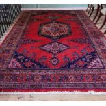 A plum red ground Persian Hammadam carpet, with central geometric lozenge, within multiple borders,