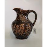 A glazed brown pottery jug, depicting drinking of ale in an ale house, with vine handle.