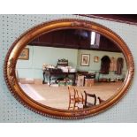 An oval decorative gilt framed wall mirror, with beaded surround.