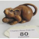 A contemporary boxwood netsuke depicting a mouse holding onto a nut.