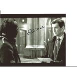 James Bond Oliver Skeete signed 10x8 black and white photo with Piers Brosnan. Good Condition. All