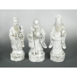 A group of three Chinese Dehua figures of Immortals, Republic Period, each standing holding an