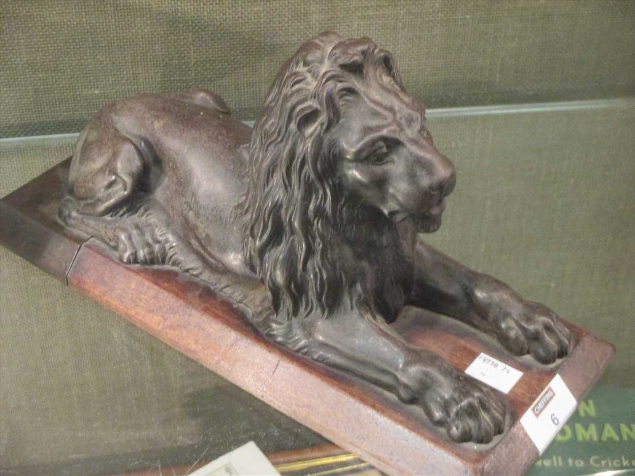 In the manner of Landseer, a bronze lion on wooden plinth