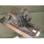 In the manner of Landseer, a bronze lion on wooden plinth