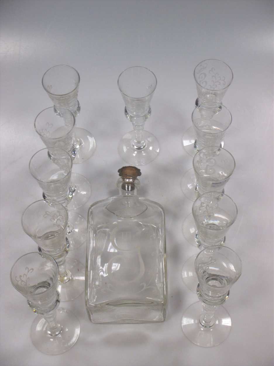 A glass cordial decanter and 11 glasses engraved with coronet above G