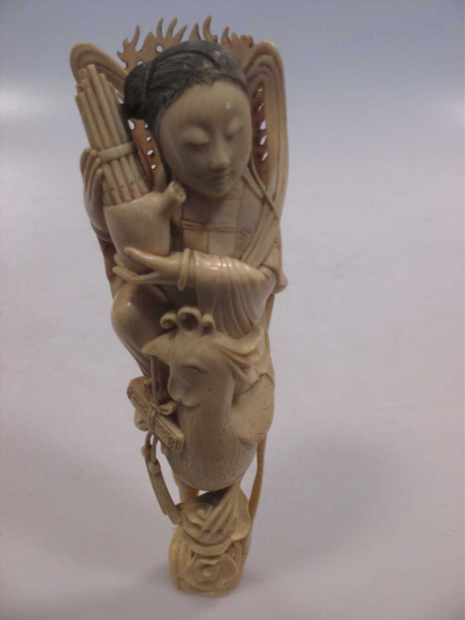 A late 19th century Japanese carved ivory figure of a girl playing a sho and seated on the back of a