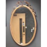 An oval gilt gesso wall mirror, with ribbon cresting, on bevelled plate (a/f, distressed)