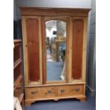 A stripped pine wardrobe, with central arched mirrored door and two drawers below, 208 x 148 x 56cm