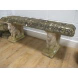 A reconstituted stone garden bench with seated lion pedestals 49 x 134 x 38cm