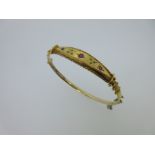 An antique hinged bangle set with small rubies and diamonds,