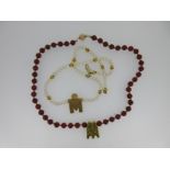 A cultured pearl necklace and a cornelian necklace each set with a Tamil wedding thali,