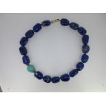 A necklace of large lapis lazuli beads and one turquoise,