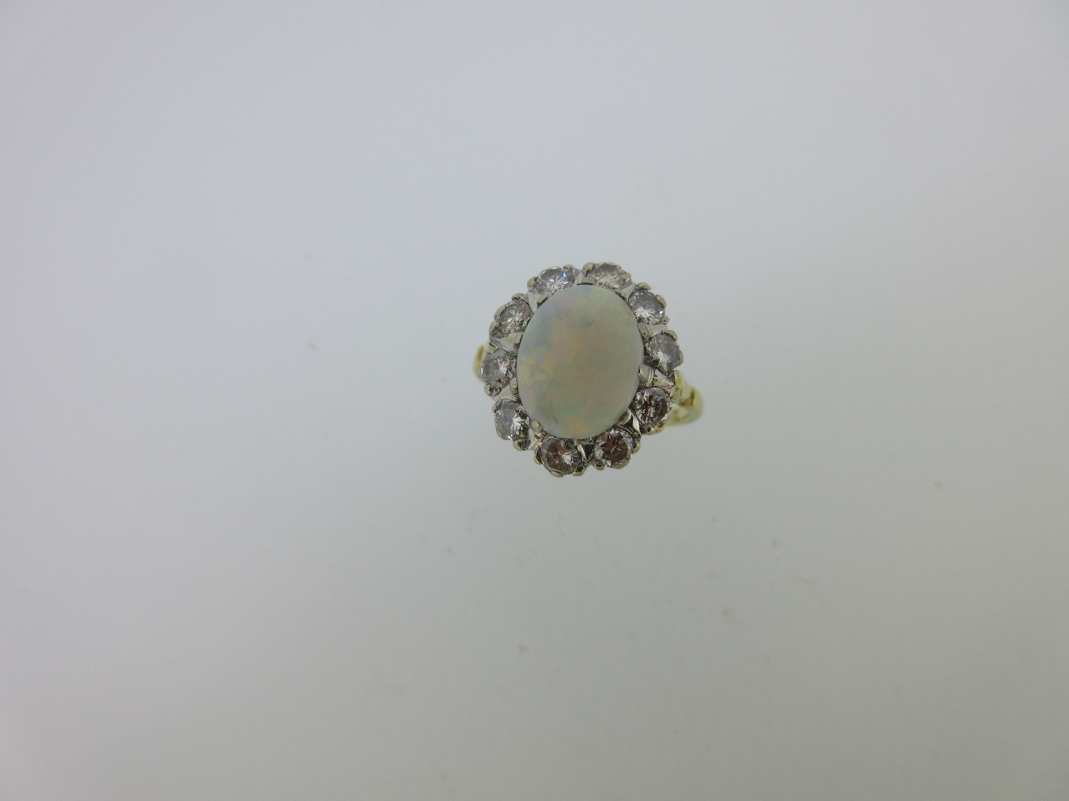 An opal and diamond cluster ring set in hallmarked gold,
