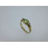A peridot and diamond three stone ring with serpent mount,