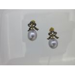 A pair of cultured pearl and diamond bow earrings,