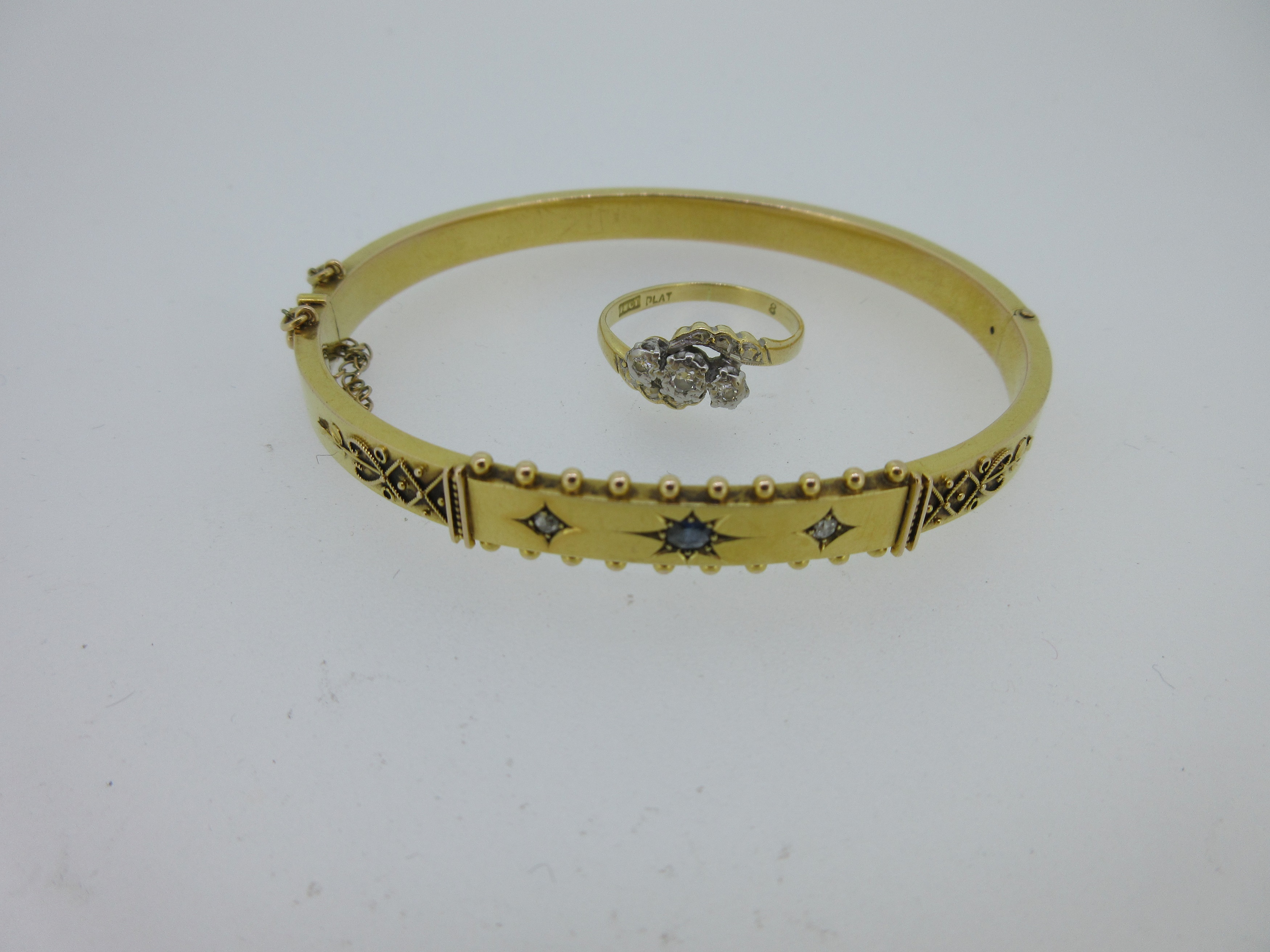 A Victorian sapphire and diamond hinged bangle together with a diamond three stone ring,