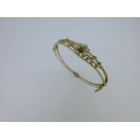 An Edwardian hinged bangle set with seed pearls and a demantoid garnet,