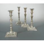 A matched set of four George II / III cast silver candlesticks,