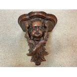 A carved walnut cherub mask wall bracket, probably 18th century,