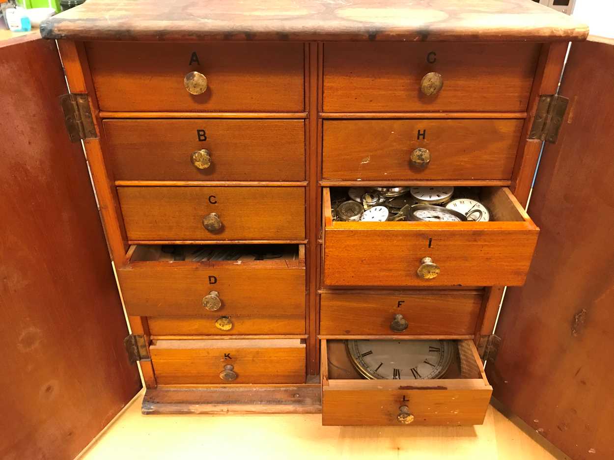 A cabinet of watchmaker's spare parts, watch movements, tools and oddments, circa 1900, the two