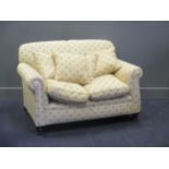 An Edwardian drop end two seat sofa, re-upholstered