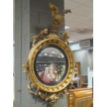 A Regency giltwood convex wall mirror, with eagle surmount, the mirror within an ebonised reeded