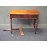 A mid 19th century mahogany fold-over tea table on four turned supports