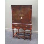 An 18th century style crossbanded walnut cabinet on stand, the two doors over a single long drawer