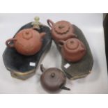 Three Chinese yixing type teapots, another of darker colour with metal spout, two glazed head-rests,