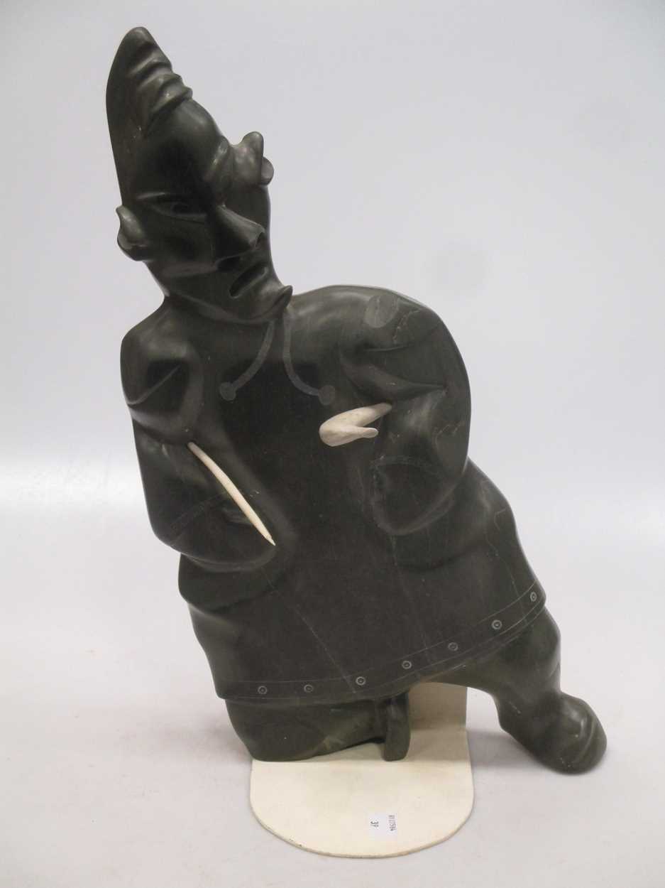 A 'Canada Eskimo Art' carved hardstone model of a hunter, with sticker to underside, on a stand,