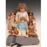 An early 20th century bisque head doll with weighted glass eyes and composition body, and 7 other