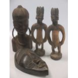 An African carved wood tribal mask, 24cm high, two male 'fetish' figures 31cm high, a crudely carved