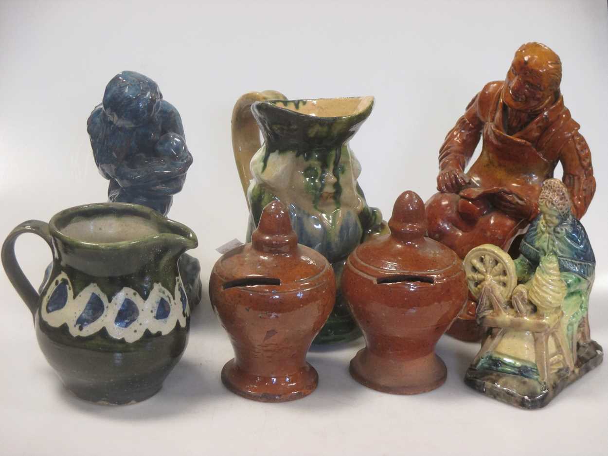 Three glazed pottery seated figures, a Toby jug, another jug, and a pair of glazed money boxes, 19th