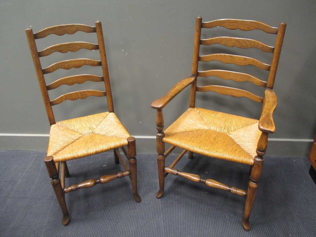 A set of ten reproduction ladder back chairs with rush seats, two elbow, eight standard.